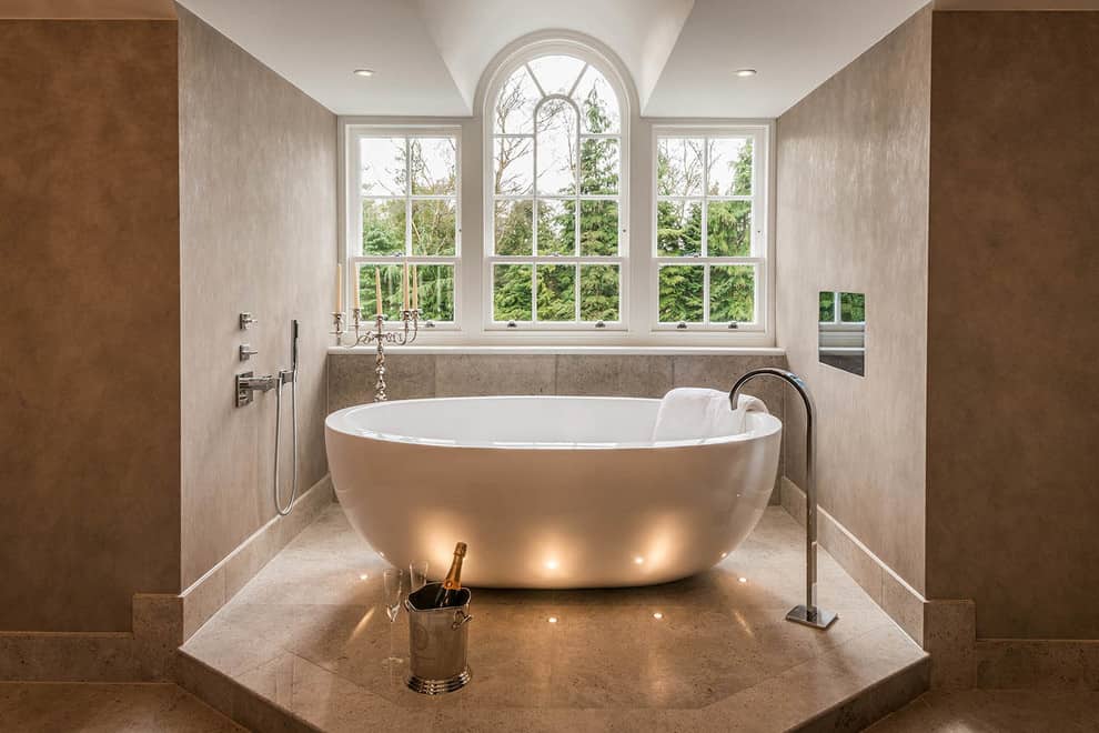 Multi-Level Lighting as Effective Way to Set Accents and Emphasize Interior. Arched window and the eggshell bathtub in the limelight of the spacious bathroom