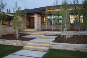 How to Increase the Security in Your Home. Modern high-tech stone-cladded house facade with LED lighting and the same lighting of the yard steps