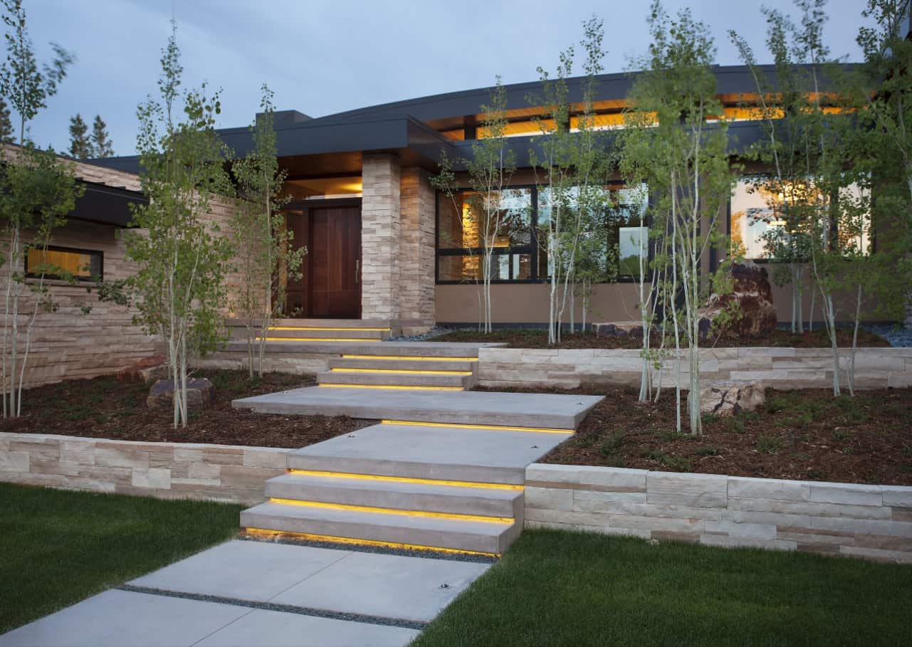 How to Increase the Security in Your Home. Modern high-tech stone-cladded house facade with LED lighting and the same lighting of the yard steps