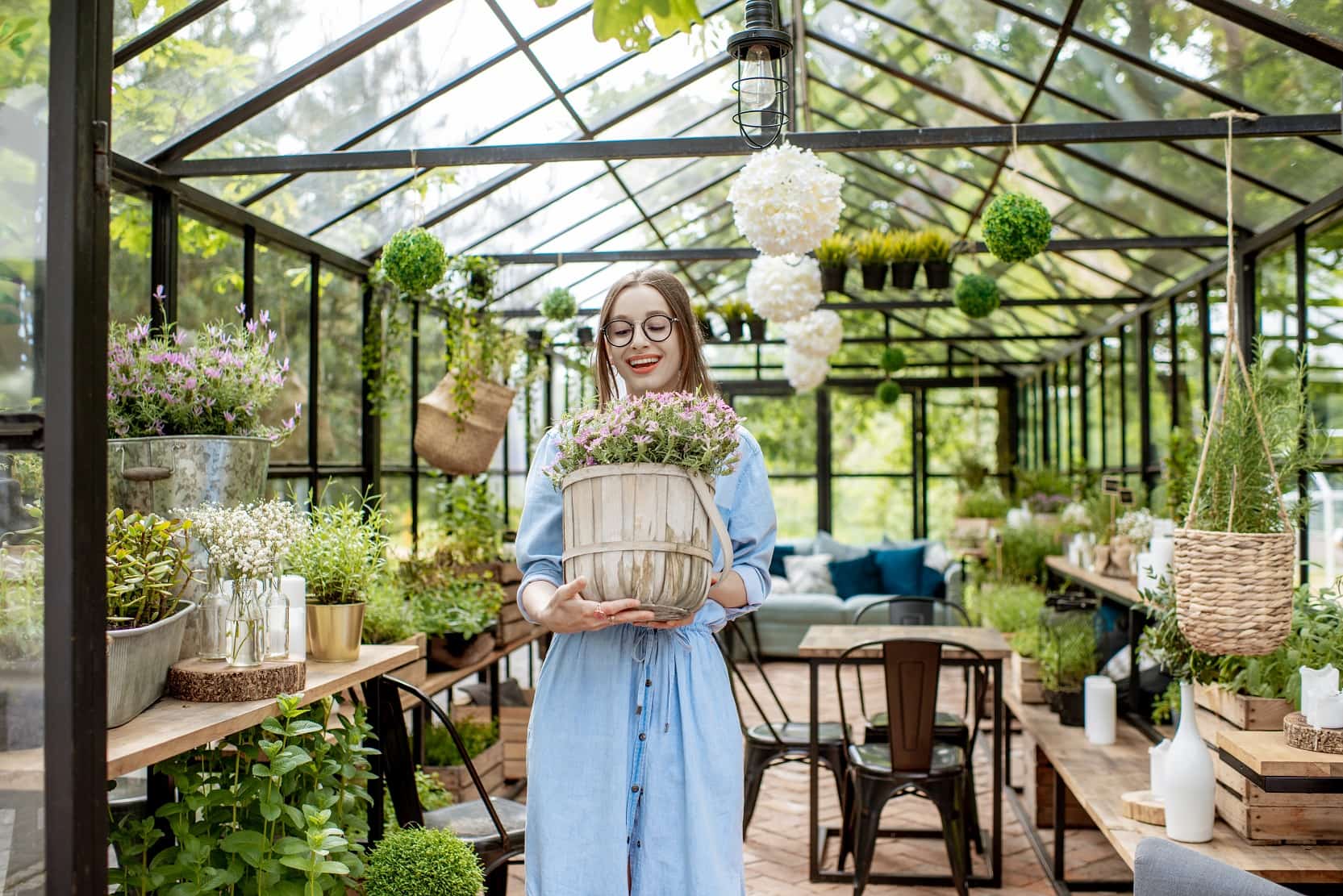 6 Benefits Of Having A Small Greenhouse In Your Home. The girl in the eco space with the bouquet of flowers in the pot
