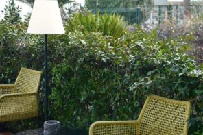 Tips to Increase the Longevity of Your Outdoor Furniture. Nice green rattan woven chairs at the wall of trimmed shrub outdoor