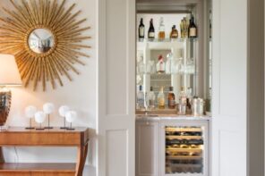 How To Create the Home Bar of Your Dreams. Starburst mirror and hidden bar as a decoration for casual styled interior with wooden floor and table
