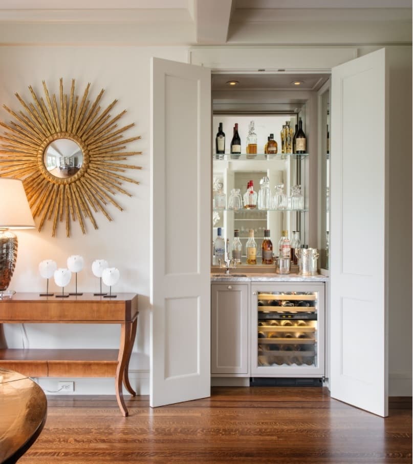 How To Create the Home Bar of Your Dreams. Starburst mirror and hidden bar as a decoration for casual styled interior with wooden floor and table