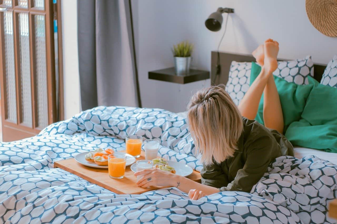 How To Choose A Perfect Bedding: Useful Tips. The blonde girl on the blue bedsheet in the modern styled room in white