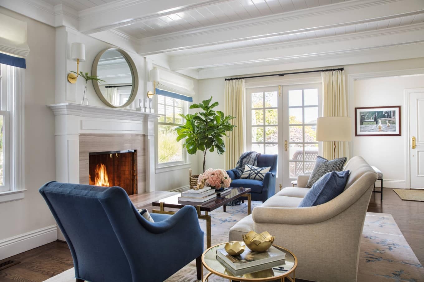 Tips for Decorating with Circular Mirrors. Blue suede furniture and mild brown tones for Classic living room with wainscoting, and the fireplace