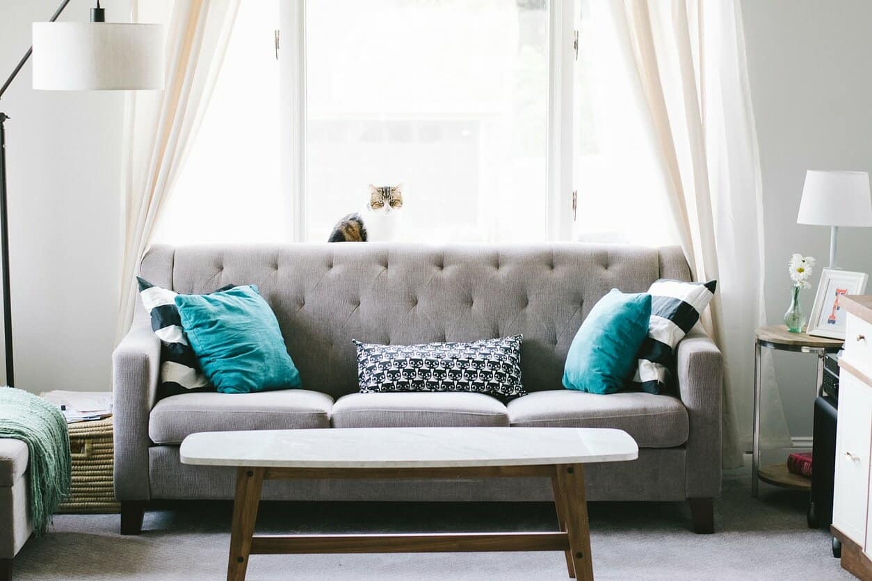 Important Things To Keep In Mind When Choosing Furniture For Your Living Room. Gray quilted sofa with turquoise pillows and gray topped wooden coffee table for the casual-style interior