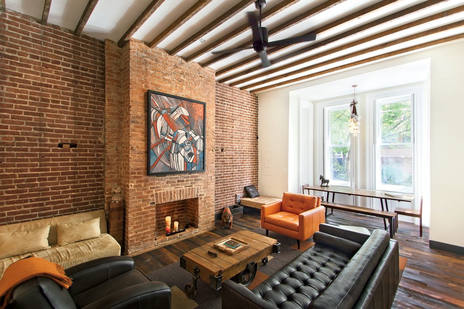 Usual brick laid wall with the fireplace and the open lattice of ceiling beams for modern loft living room