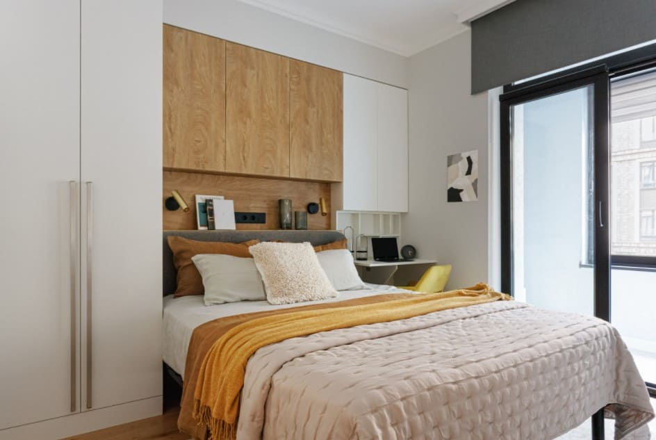 Tiny 100 Square Feet Bedroom Effective and Laconic Design Ideas. Scandinavian minimalism in the bedroom with headboard wooden panel, large king size bed and even a small working space next to it