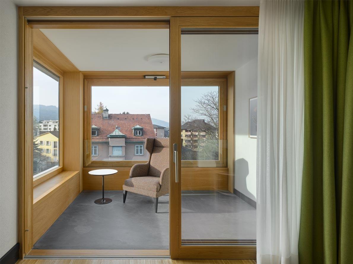 Light wooden frames of doors and panoramic windows for modern white painted balcony