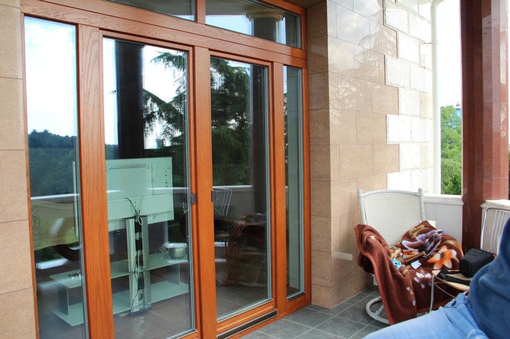 Choosing the Balcony Doors: Construction, Design, and Color. Light brown wooden door frame
