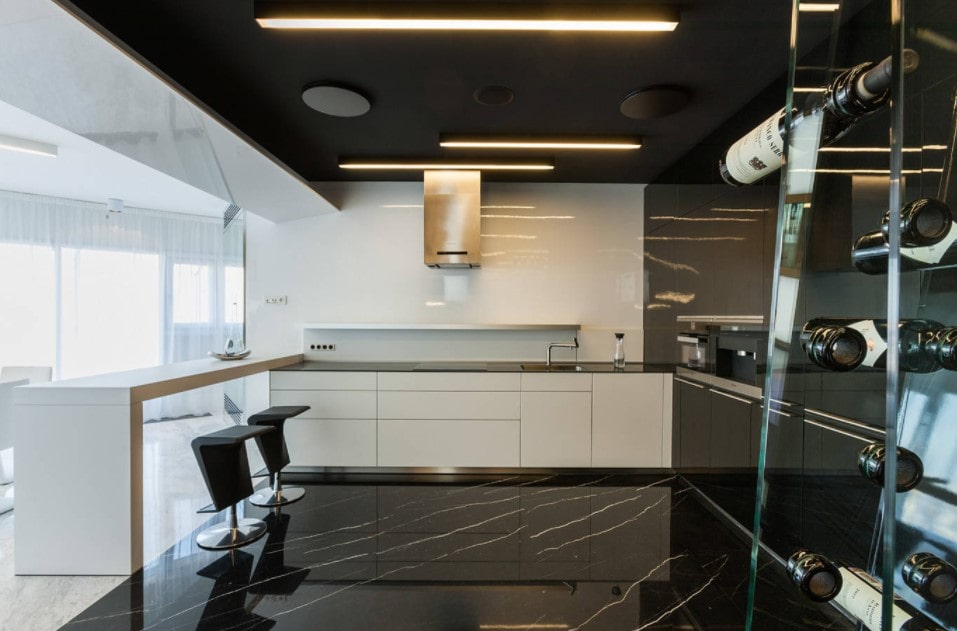Black and white ultramodern kitchen with LED ceiling panels and glossy tiles at the floor