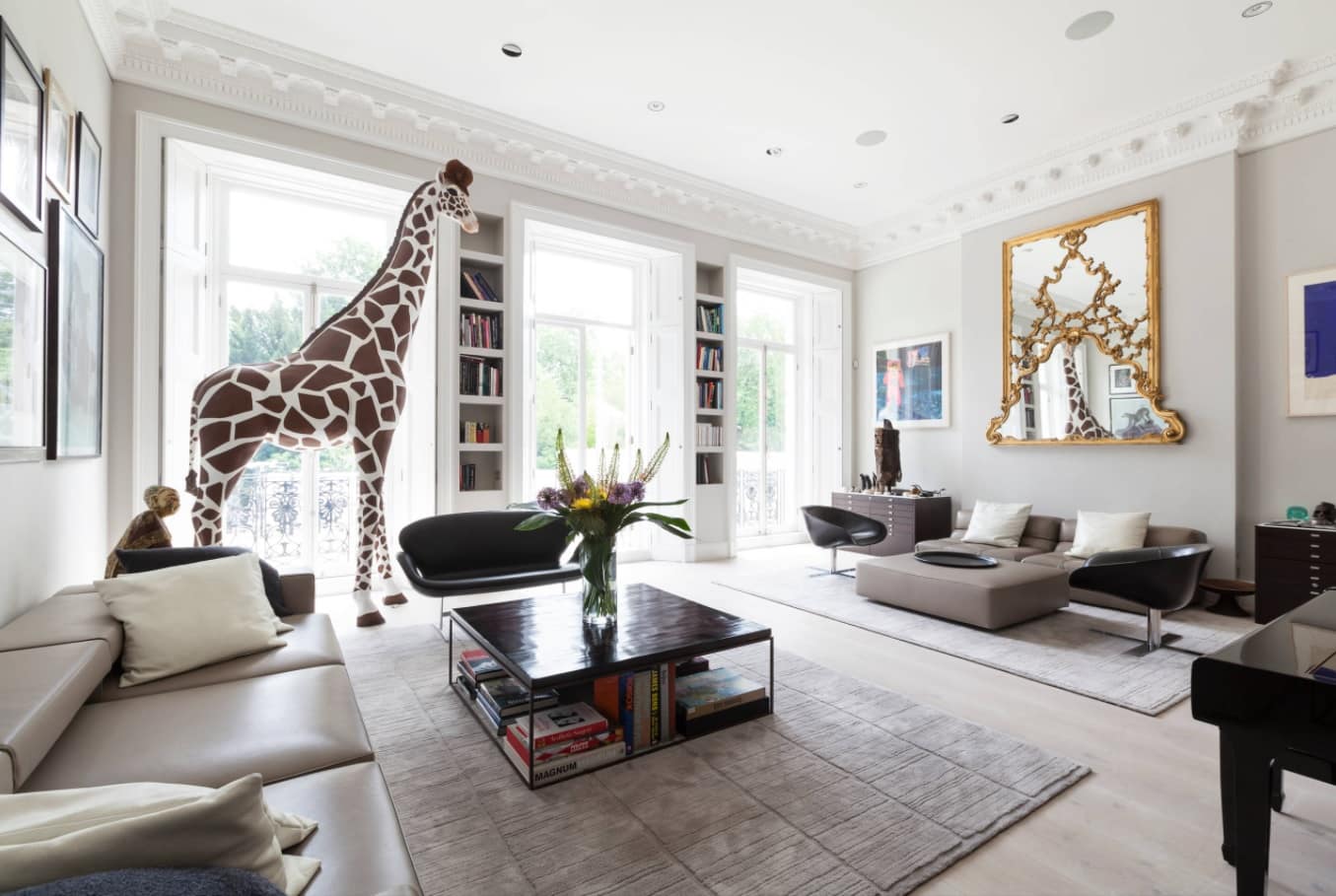 5 Easy Ways To Refresh Your Living Room Without Breaking the Bank. Interior decorations in the form of large figurines and gilded mirror for chic design of the living with book shelves in the partitions between the windows