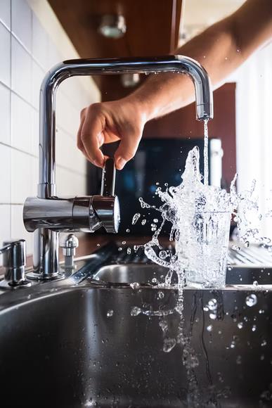 Beginner’s Guide: Choosing the Right Kitchen Faucet. The water spashes out of the glass at the double steel sink