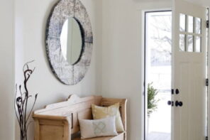 4 Ways to Create a Beautiful and Functional Entryway. Round mirror in solid wooden frame and contrasting light wooden bench for pastel white classic entryway