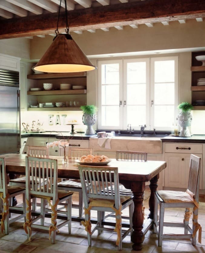 7 Ideas for Creating an Eat-in Kitchen for Entertaining. Country style kitchen with large wooden table, white classic chairs, open shelves and dark countertop