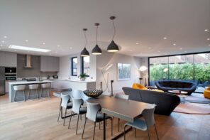 Exhaust Smell in the House: How to Get Rid of It. Unusual common kitchen space in mild gray and matte white with natural wooden laminated floor