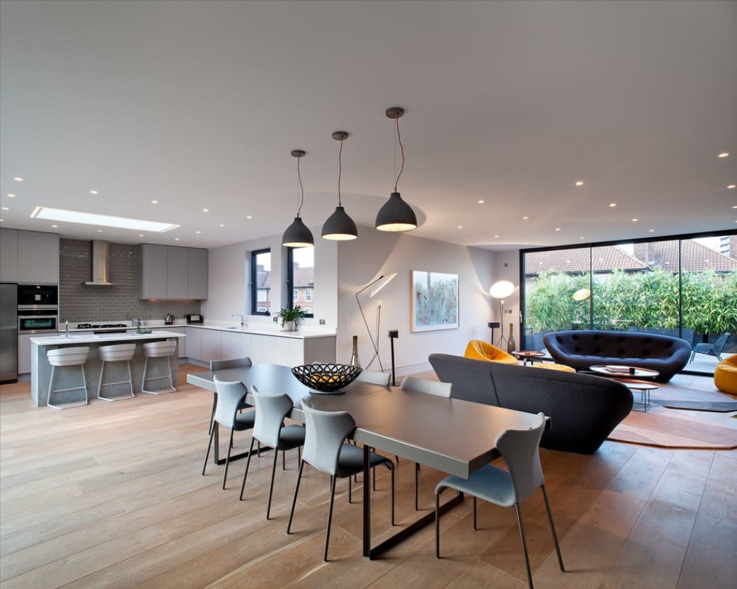 Exhaust Smell in the House: How to Get Rid of It. Unusual common kitchen space in mild gray and matte white with natural wooden laminated floor