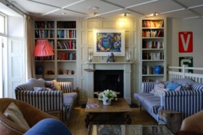 A Guide to Choose the Perfect Art For Each Room of Your Home. Library looking calming living room with the protruding fireplace and the illuminated picture above it