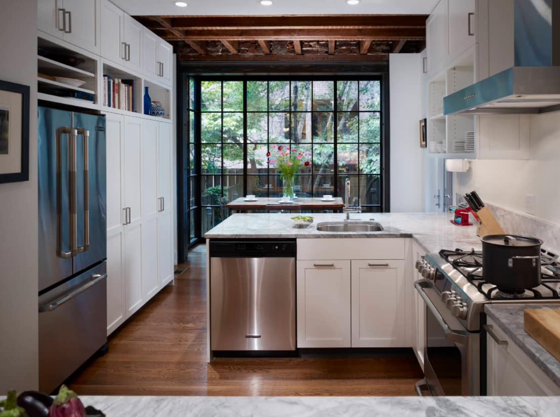 The Insider’s Guide - Dishwasher Installation Done Right. Classic L-shaped kitchen in the private house with white furniture, steel appliances and stunning panoramic sash window with black frame