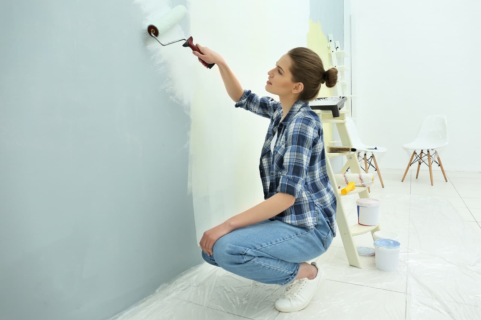 DIY Interior Paint: 7 Tips And Tricks For A Flawless Finish. The woman painting the wall with the roller