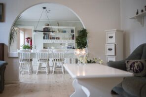 6 Examples Of How Furniture Can Double Up Its Use. White painted wooden furniture in the classic open space interior with arch to the dining room