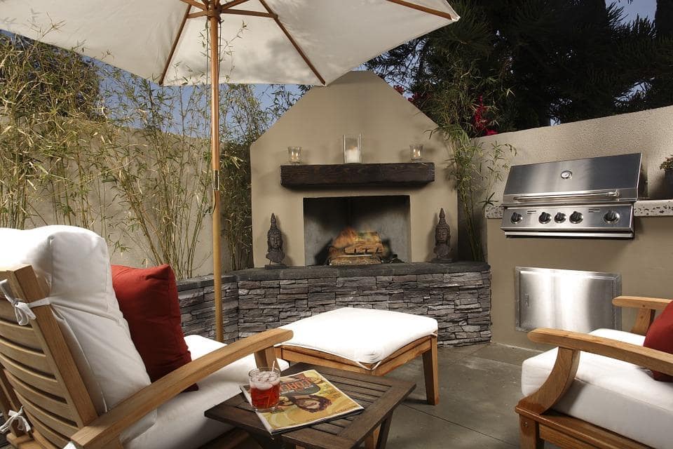 How DIY Enthusiasts Can Set up an Outdoor Kitchen to Enjoy Their Healthy Recipes. Modern BBQ zone with the stove, umbrella and chaise longue