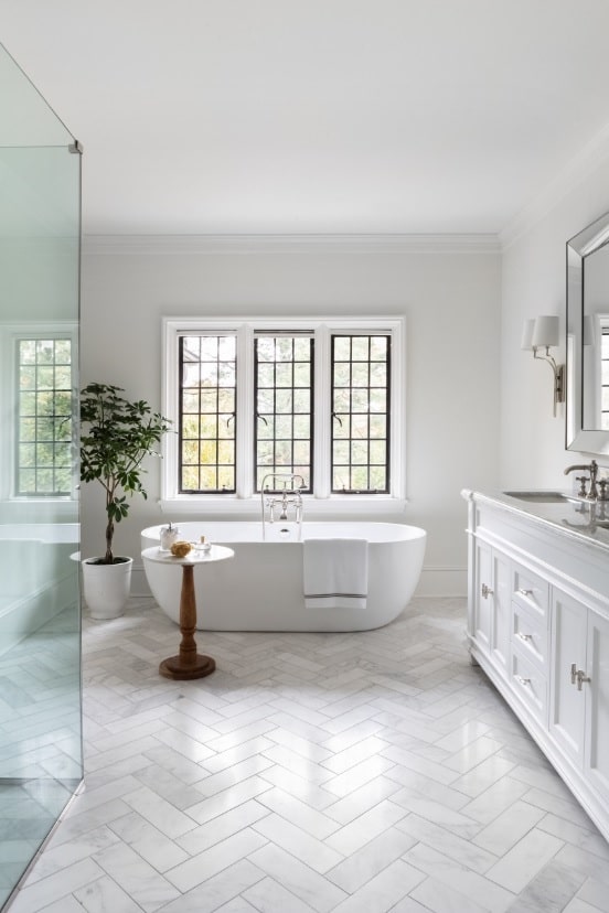 5 Tiny Details That Make or Break Your Bathroom Look. Smooth marble imitating floor, the plant in a pot, contrasting sash window for the classic white interior with glass shower